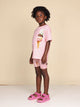 Kind in SNURK Ice Cream Cones Bikershorts Kids en roze shirt met ijsjesprint, perfect voor spelen en slapen.