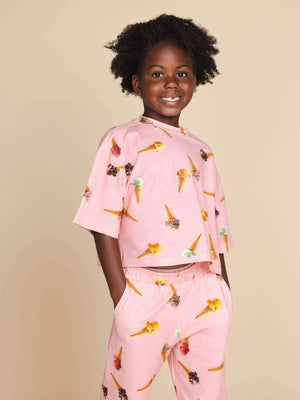 SNURK Ice Cream Cones Cropped T-Shirt Kids, kind in een roze shirt met ijsjes, perfect voor comfort en stijl.