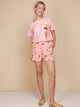 SNURK Ice Cream Cones Shorts Dames model in roze outfit met ijsjesprint op achtergrond.