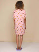Model met krullend haar draagt de SNURK Ice Cream Cones T-shirt Dress Dames, roze met ijsjesprint.