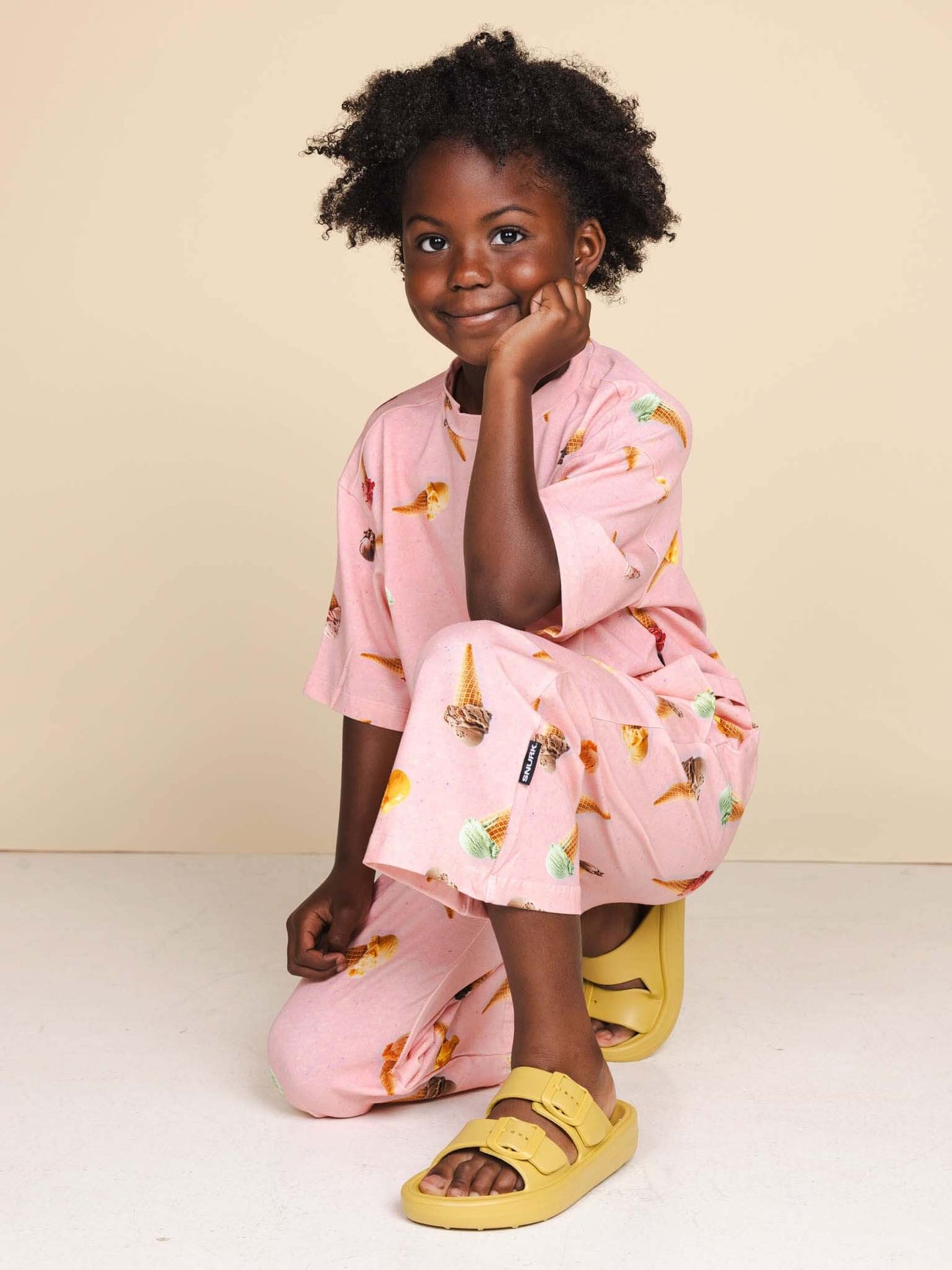 SNURK Ice Cream Cones Wide Pants Kids - Een meisje draagt een broek met ijsjes in een ontspannen houding.