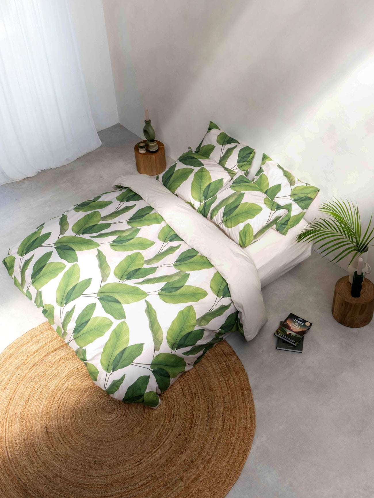 SNURK Leaf Me dekbedovertrek met bladerenprint op bed in tropische sfeer.