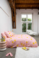 SNURK Lemon dekbedovertrek met gele citroenen op een roze dekbed in een moderne slaapkamer.