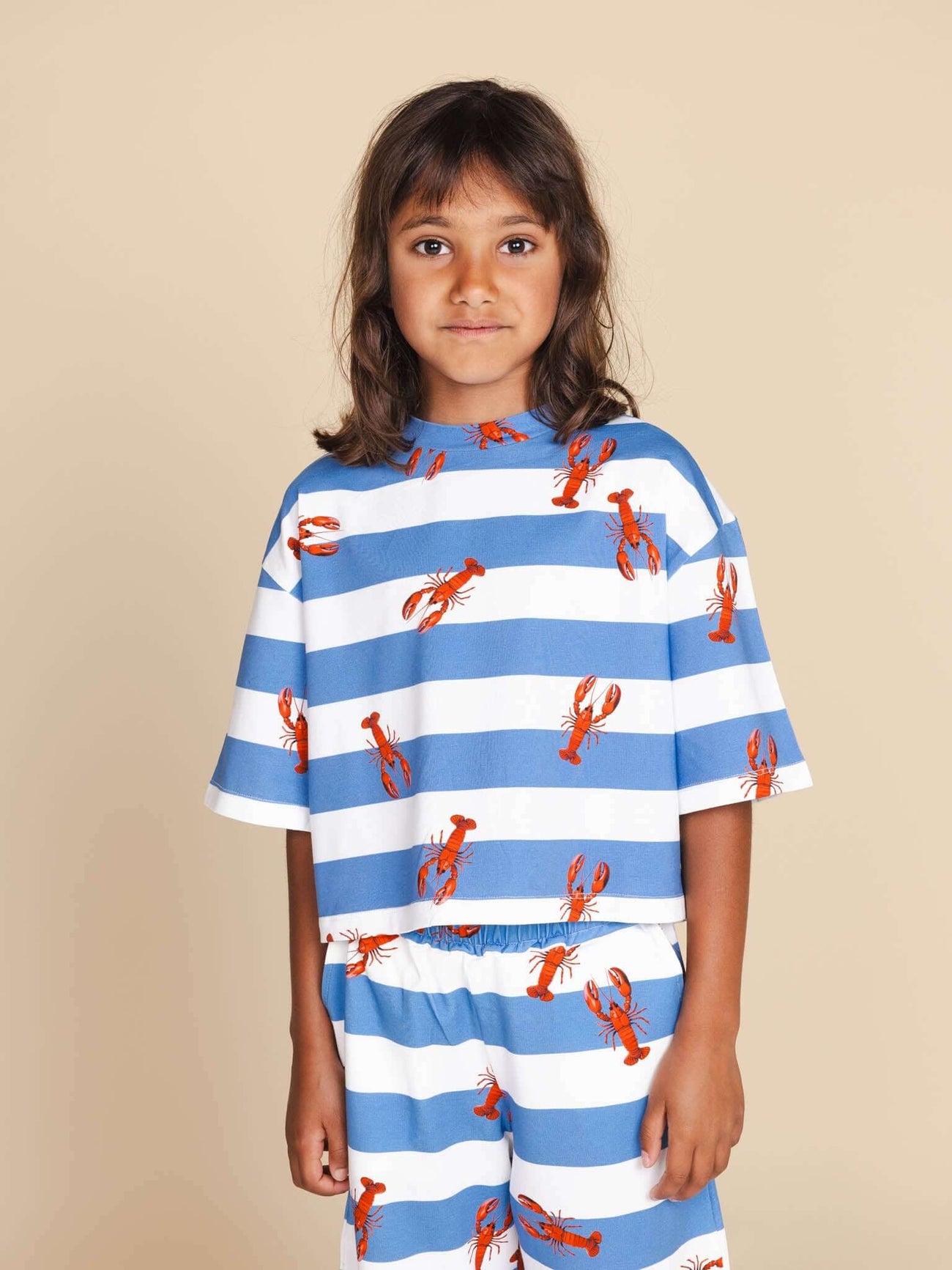 Kind in SNURK Lobsters Cropped T-Shirt Kids met blauwe strepen en kreeftjesprint.
