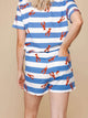 Vrouw draagt SNURK Lobsters Shorts Dames met rode kreeftjes op blauwe strepen, ideaal om te loungen.
