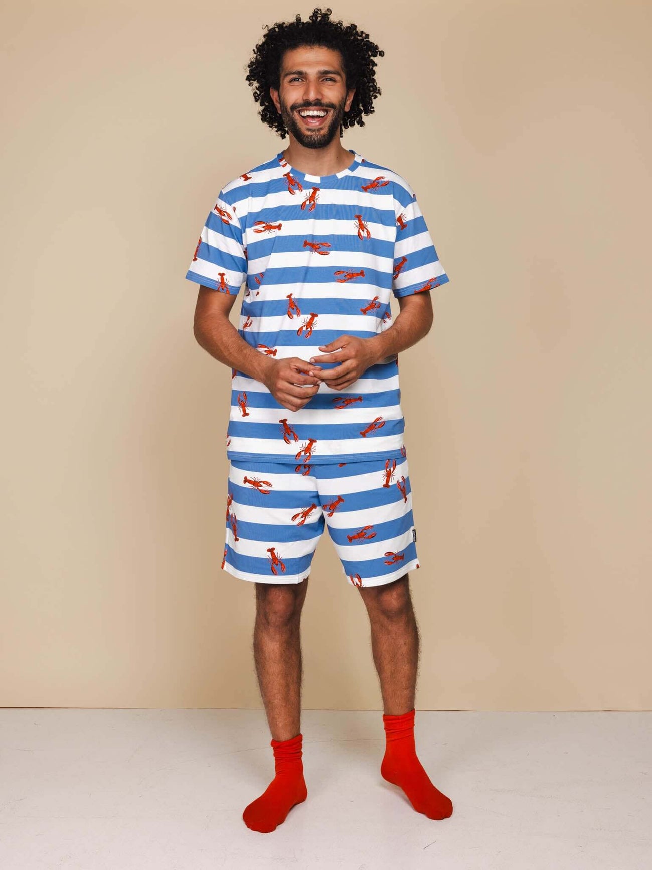 SNURK Lobsters Shorts Heren model in blauwe gestreepte short met rode kreeftjes en rode sokken.