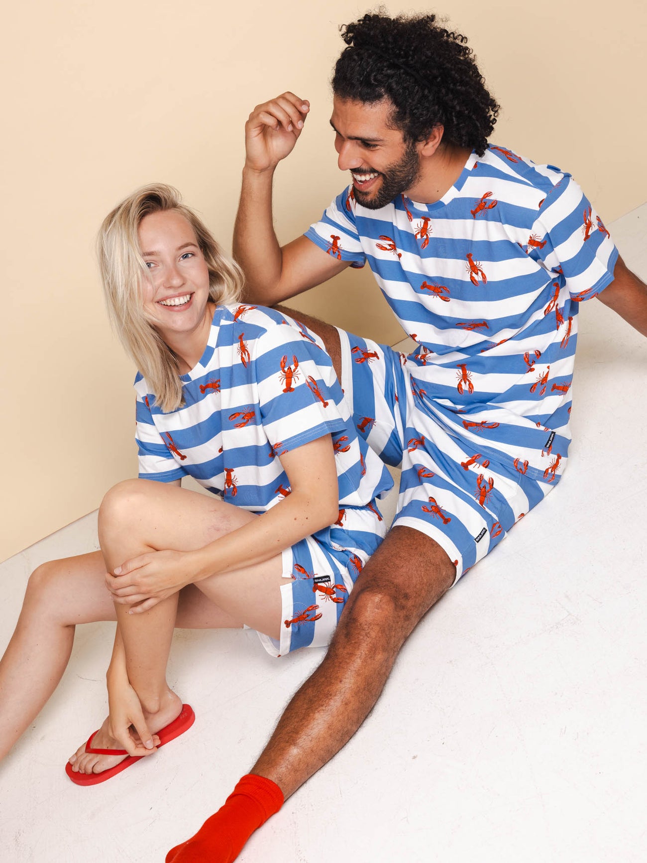 SNURK Lobsters T-shirt Unisex in blauw gestreept design, gedragen door een man en vrouw, perfect voor casual look.
