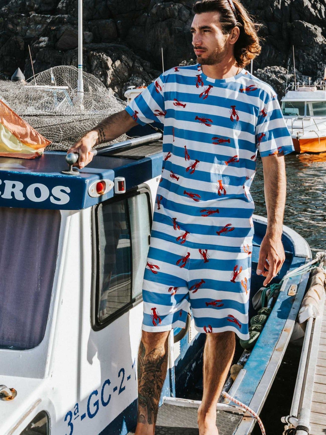 SNURK Lobsters T-shirt Unisex op een boot met kreeftjes en blauwe strepen.