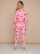 Achteraanzicht van een kind in de SNURK Lollipop Love Broek Kids met felrode hartjes op een roze achtergrond.