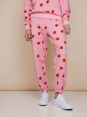 SNURK Lollipop Love Broek Relaxed Unisex met felrode hartjeslollies op roze.