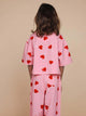 A child wearing the SNURK Lollipop Love Cropped T-Shirt Kids with red heart lollipops on pink, showcasing a fun design.