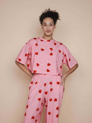 SNURK Lollipop Love Cropped T-shirt Dames met schattige hartjeslollies op een roze achtergrond.