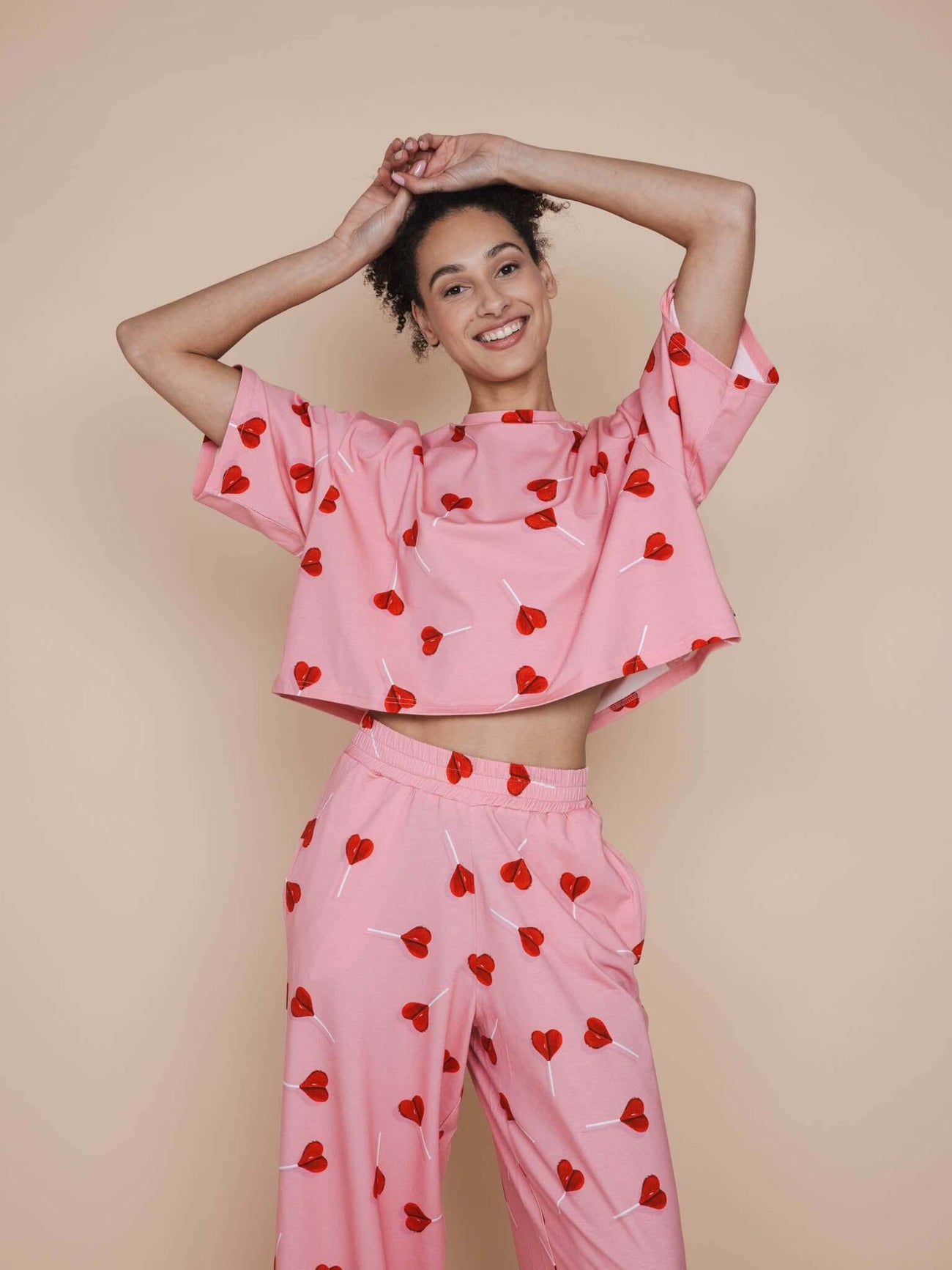 SNURK Lollipop Love Cropped T-shirt Dames model in roze shirt met hartjeslollies.