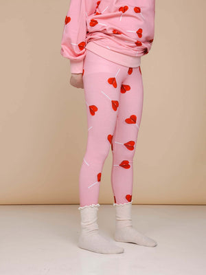 SNURK Lollipop Love Legging Kids met felrode hartjeslollies op roze achtergrond voor een vrolijke look.