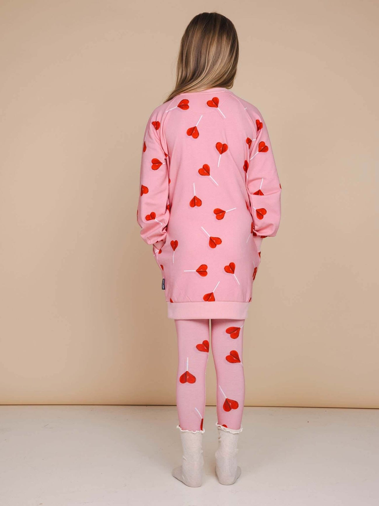Meisje in roze SNURK Lollipop Love Legging Kids met hartjeslollies print, gezien van achteren.