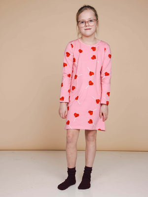 SNURK Lollipop Love Long Sleeve Dress Kids met felrode hartjeslollies op een roze achtergrond.