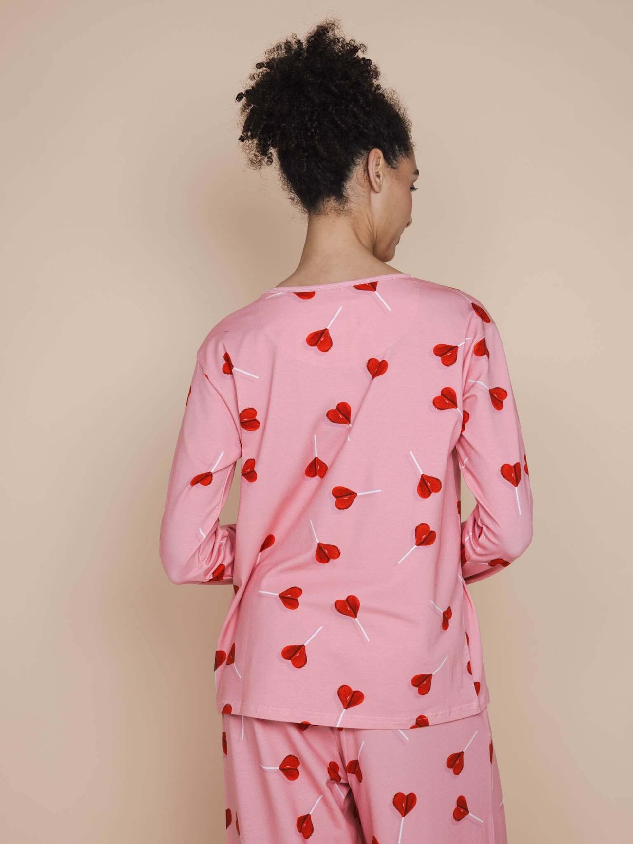 SNURK Lollipop Love Long Sleeve T-shirt Dames met felrode hartjeslollies op roze stof, relaxte fit en lange mouwen.