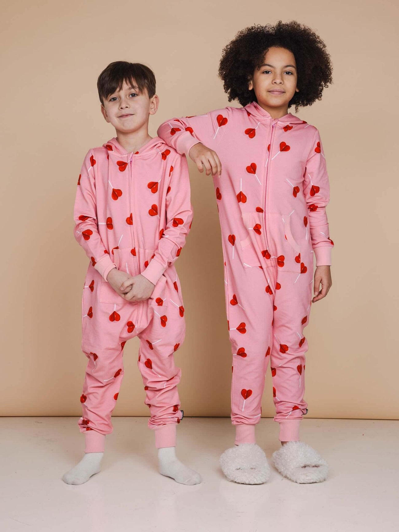 SNURK Lollipop Love Onesie Kids in roze met hartjesprint, perfect om te slapen en te spelen.