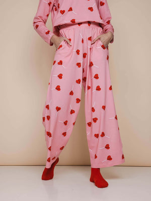 SNURK Lollipop Love Wijde broek Dames met felrode hartjeslollies op roze achtergrond, relaxte fit en zachte stretch.