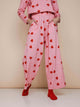 SNURK Lollipop Love Wijde broek Dames met felrode hartjeslollies op roze achtergrond, relaxte fit en zachte stretch.