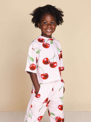 SNURK Mon Cherry Cropped T-Shirt Kids, kind in een T-shirt met kersjesprint, perfecte outfit voor pyjama of school.