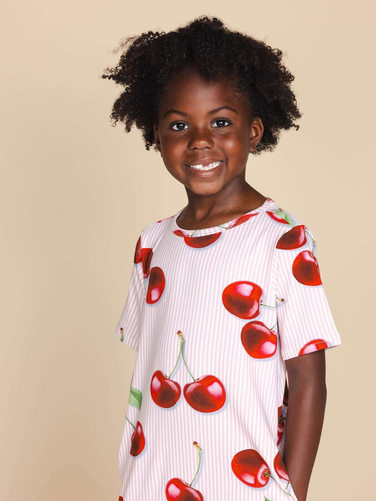 SNURK Mon Cherry T-shirt Dress Kids model in een vrolijk shirt met rode kersjes en een relaxte pasvorm.