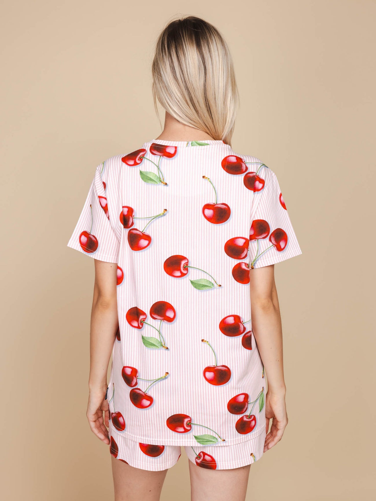 Achteraanzicht van een vrouw in het SNURK Mon Cherry T-shirt Unisex met een kersenprint.