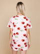 Achteraanzicht van een vrouw in het SNURK Mon Cherry T-shirt Unisex met een kersenprint.