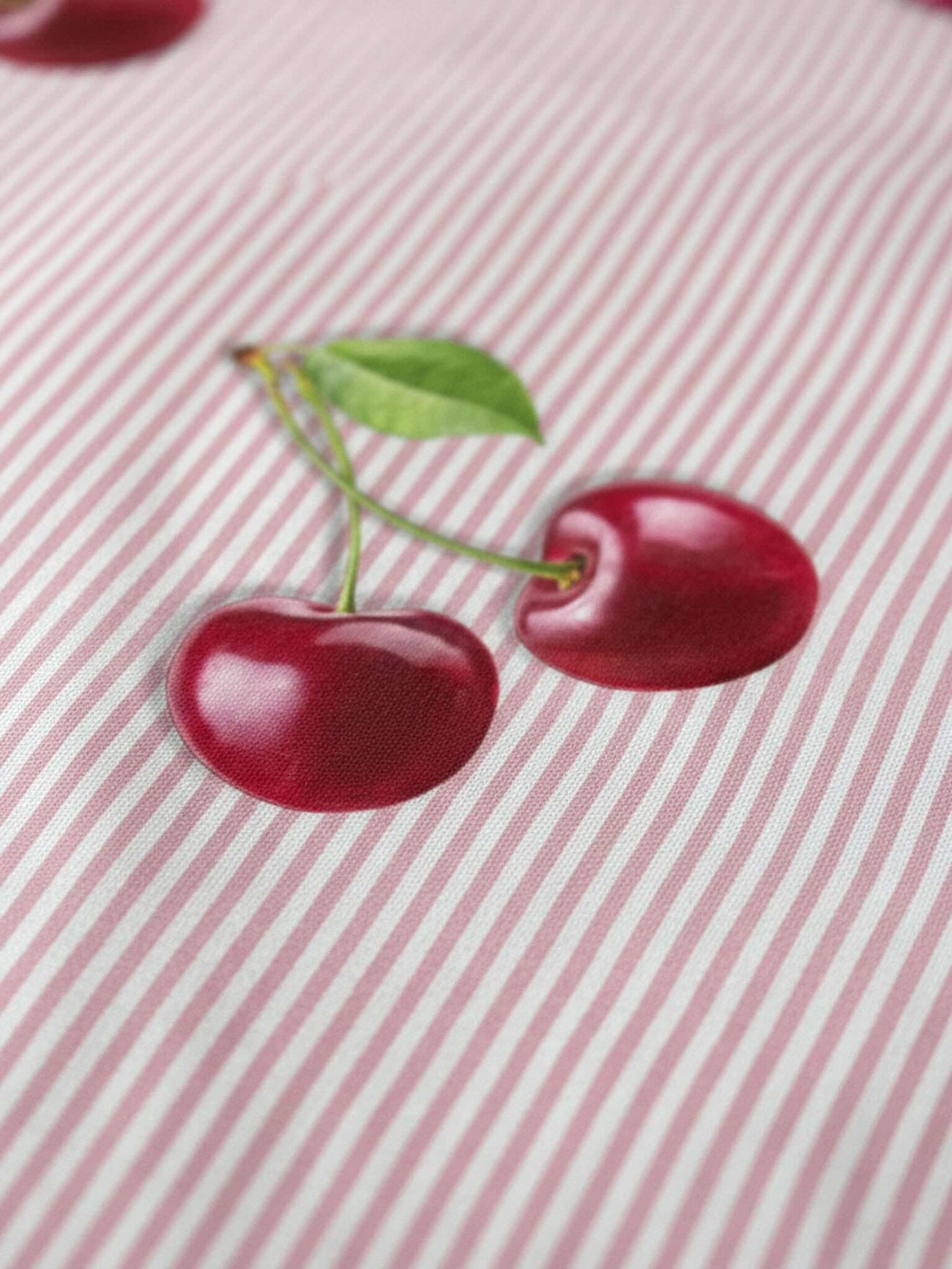 SNURK Mon Cherry dekbedovertrek met twee kersen op een roze gestreepte achtergrond.