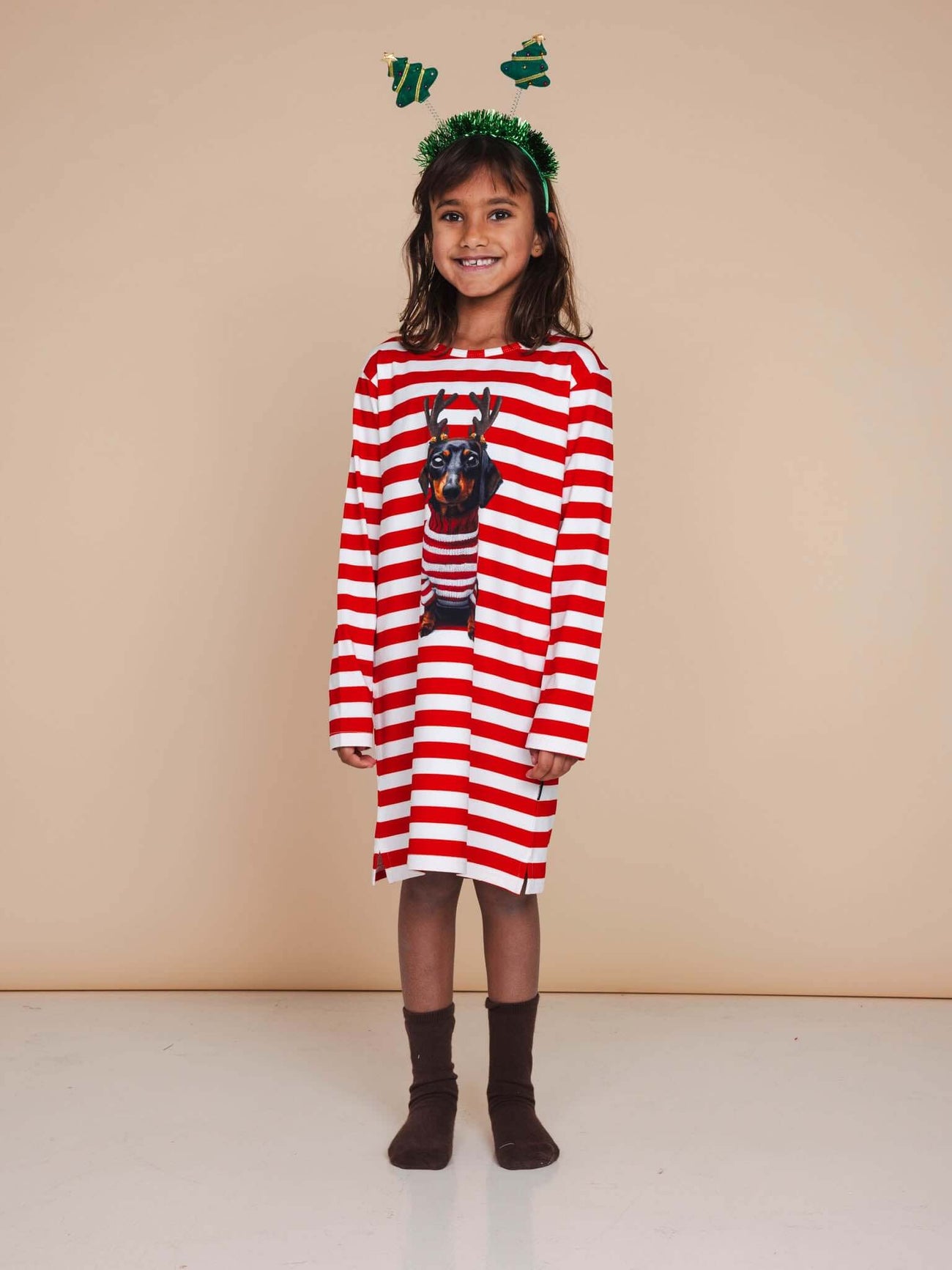 Meisje in SNURK Pierre Xmas Long Sleeve Dress Kids met kersthoofdtooi in een sfeervolle setting.