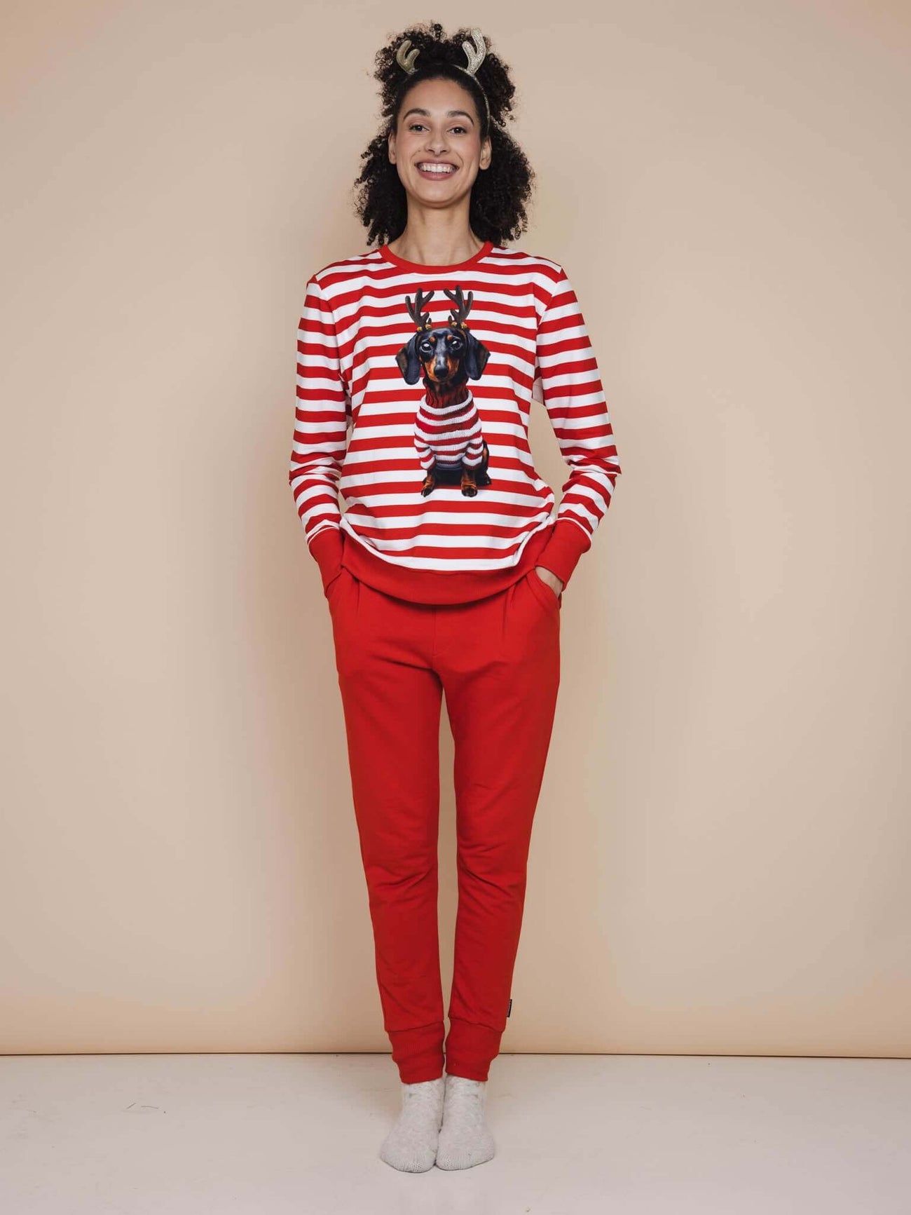 SNURK Pierre Xmas Sweater Dames model in gestreepte sweater met hond en rode broek, perfect voor de feestdagen.