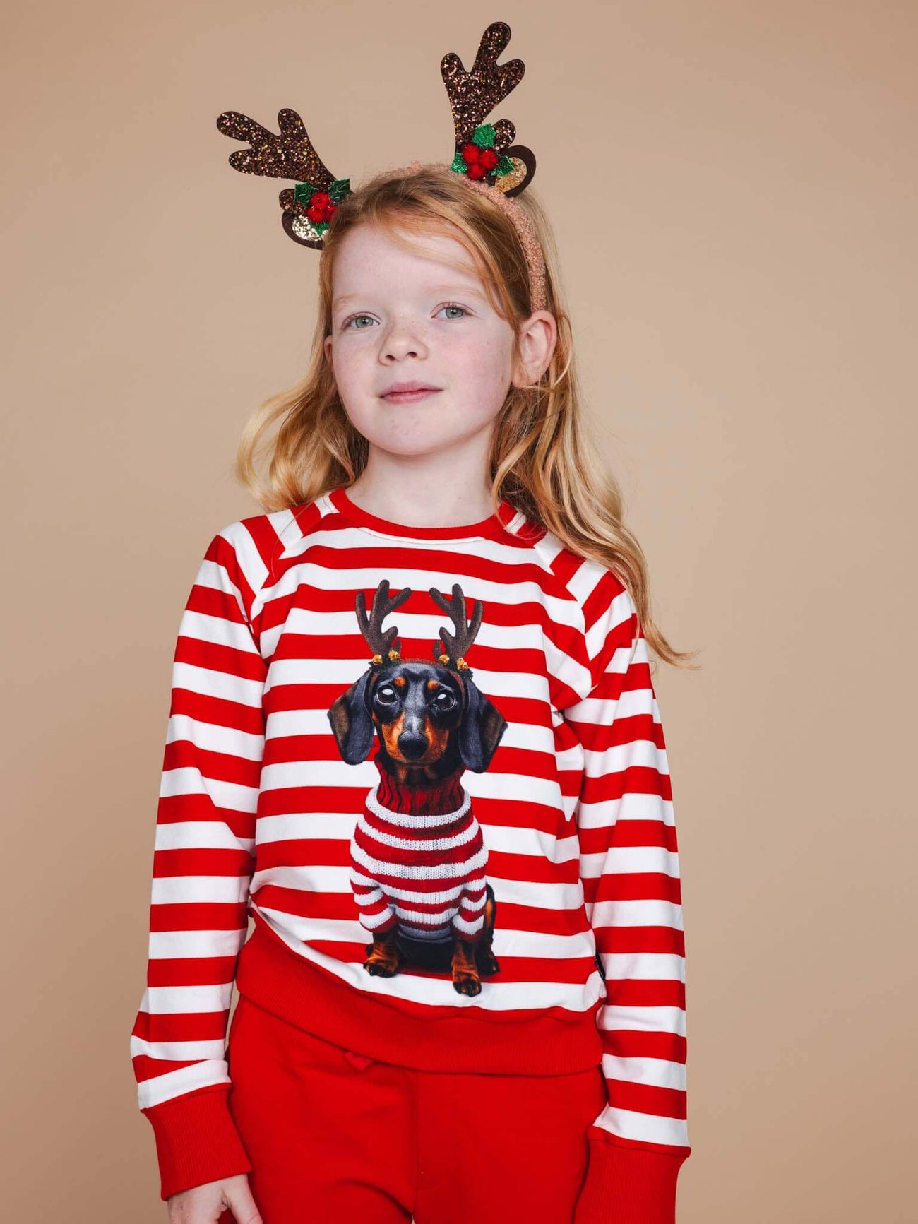 SNURK Pierre Xmas Sweater Kids met een kind in een gestreepte kersttrui en rendierhoornen.