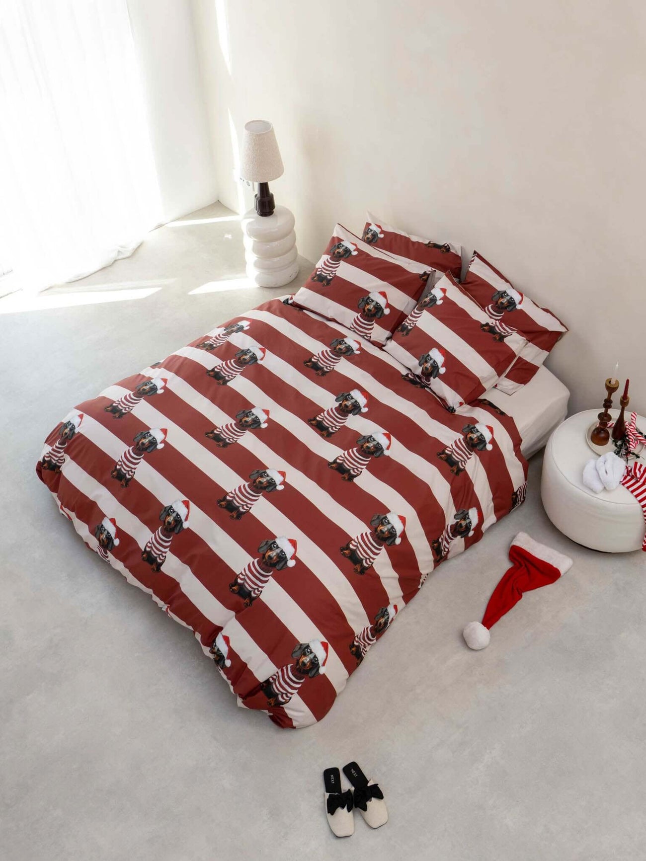 SNURK Pierre Xmas dekbedovertrek met teckel en kerstmuts op een bed met gestreepte dekbedovertrek.