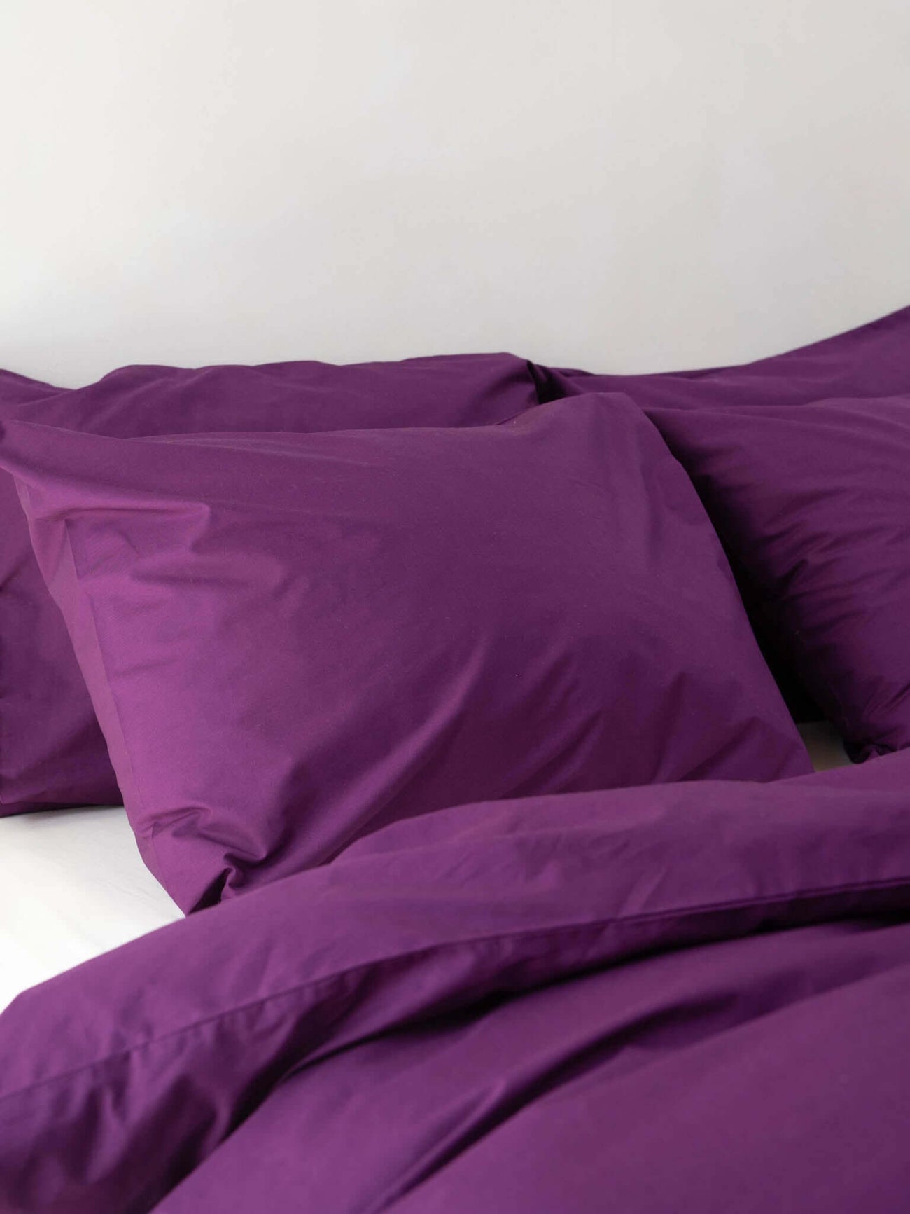 SNURK Plum Purple dekbedovertrek met paars dekbed en kussens in een moderne slaapkamer.