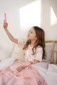 Meisje in bed met SNURK Princess Beige dekbedovertrek, speelt met een roze toverstaf.