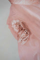 Detaillering van een roze jurk met bloemen op de taille.