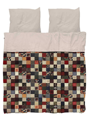 SNURK Quilty Pleasure dekbedovertrek met kleurrijk patchwork design en lichte kussenslopen voor een vrolijke slaapkamer.