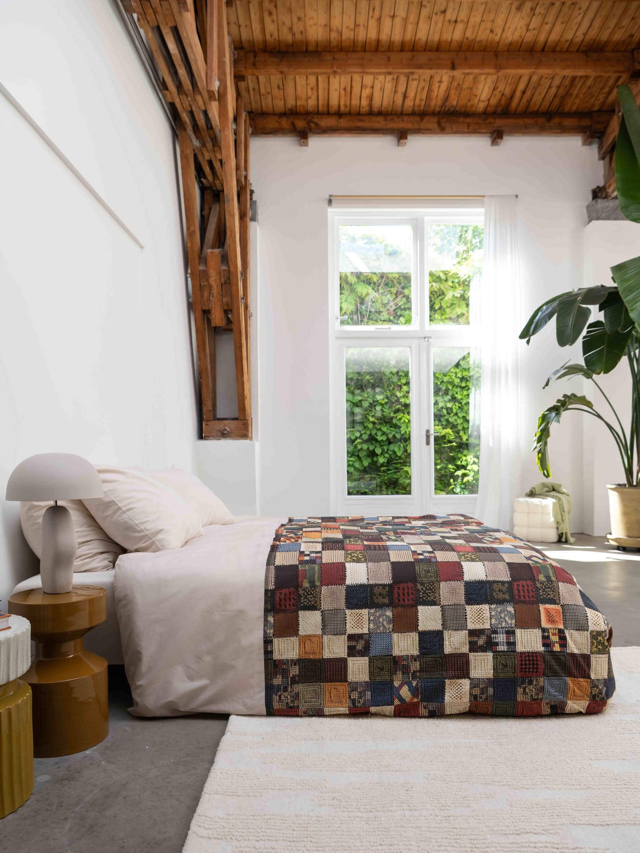 SNURK Quilty Pleasure dekbedovertrek in een moderne slaapkamer met houten balken en planten.