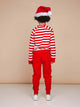 Een kind in een gestreepte trui en SNURK Red Broek Kids met een kerstmanmuts, perfect voor de feestdagen.