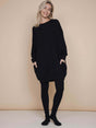 Model draagt de SNURK Slow Black Sweater Dress Dames met leggings op een neutrale achtergrond.