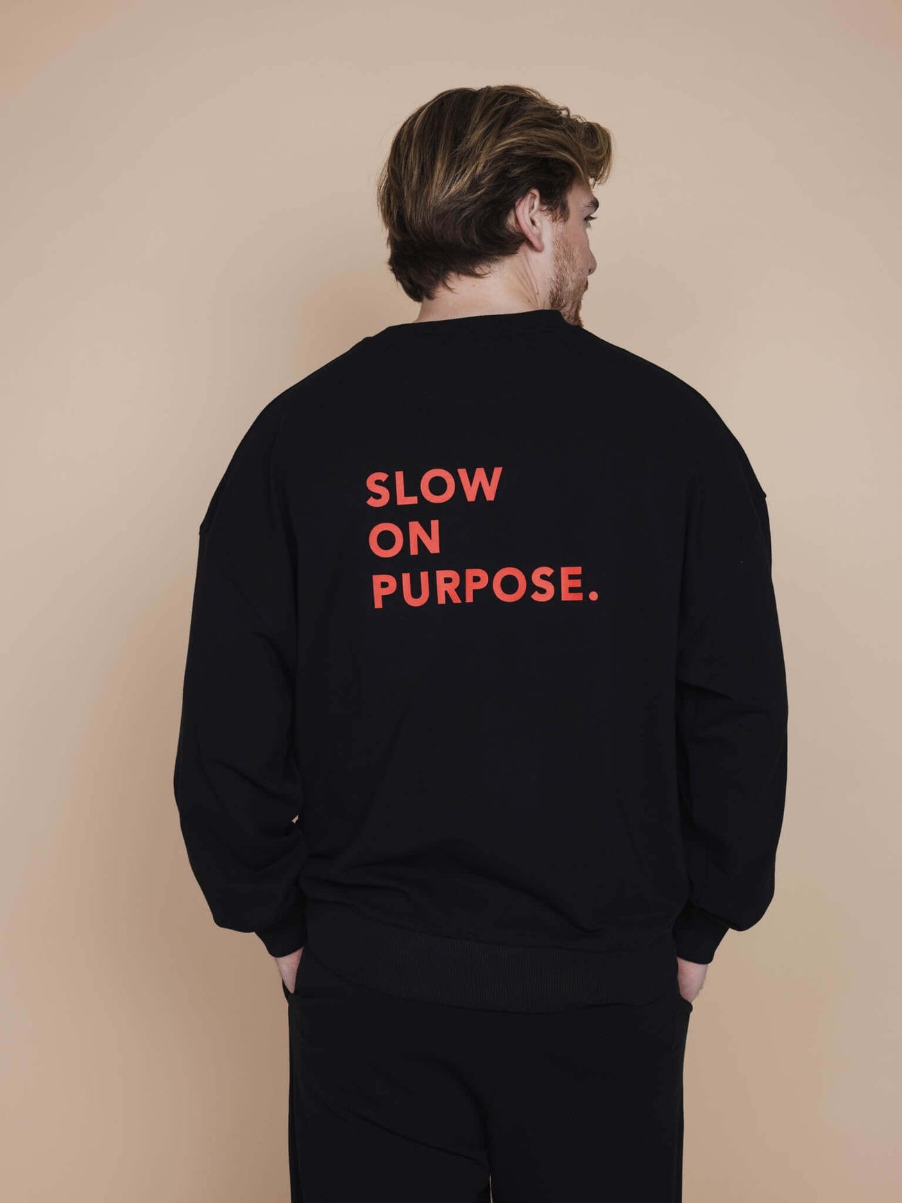 SNURK Slow Black Sweater Heren met de tekst 'SLOW ON PURPOSE' op de rug, perfecte relaxday outfit.