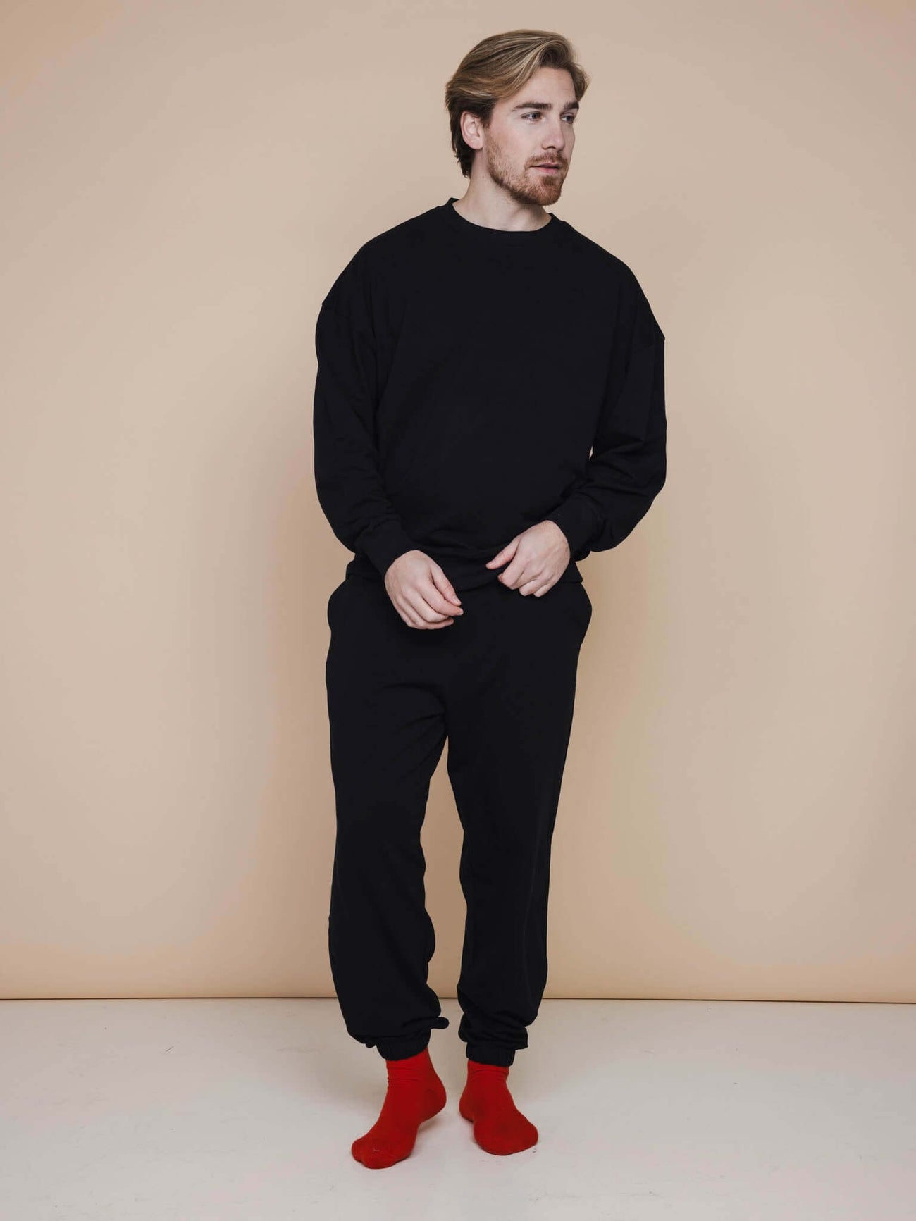 SNURK Slow Black Sweater Heren worn by a man with red socks, relaxed fit, soft organic cotton, perfect for leisure.
