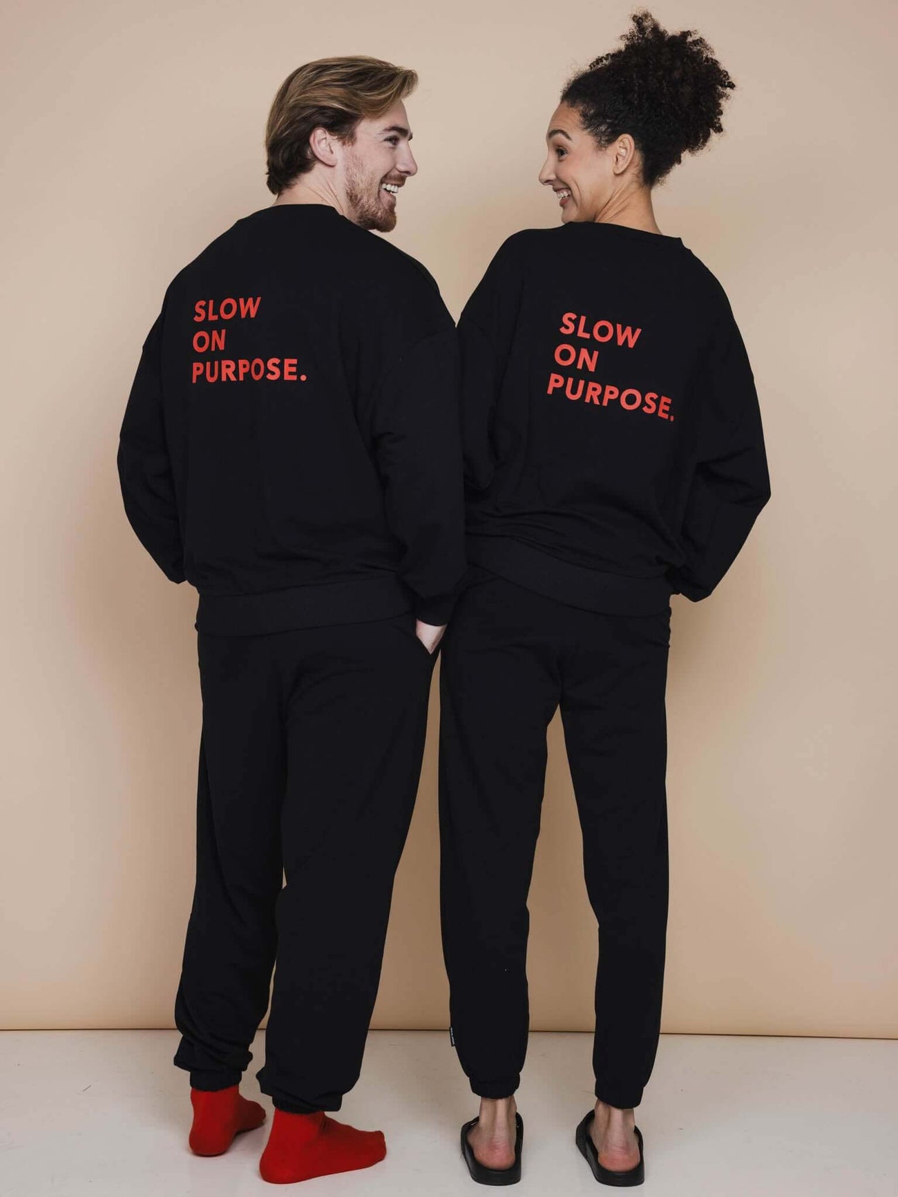 SNURK Slow Black Sweater Unisex model show, featuring 'SLOW ON PURPOSE' on the back in bright red.