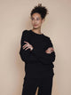 SNURK Slow Black Sweater Unisex model in zwarte sweater met relaxed-fit en raglanmouwen.