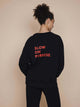 SNURK Slow Black Sweater Unisex met de tekst 'SLOW ON PURPOSE' op de rug in heldere letters.