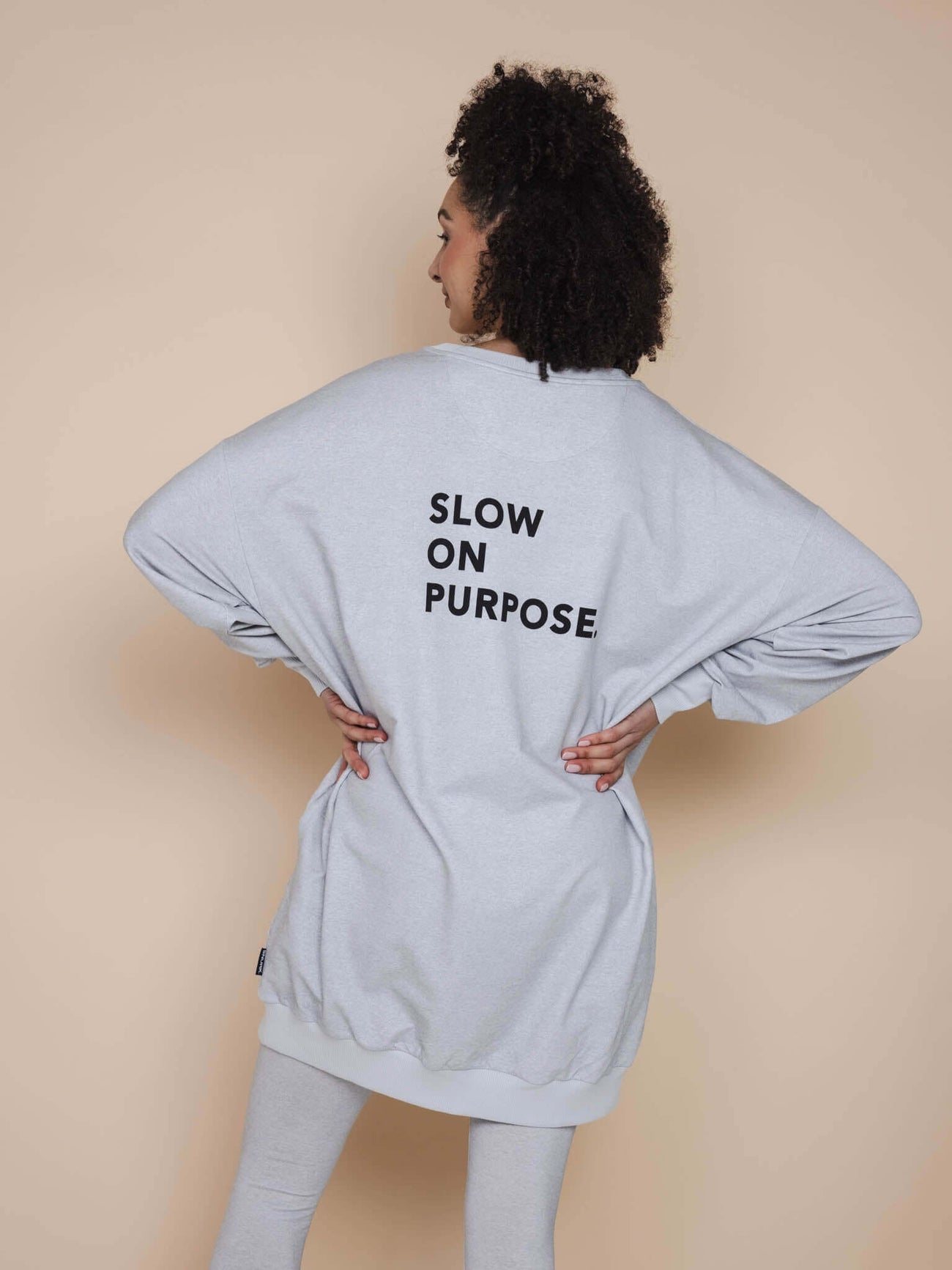 SNURK Slow Grey Sweater Dress Dames met de tekst 'SLOW ON PURPOSE' op de rug in grijze kleur.