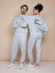 SNURK Slow Grey Sweater Unisex worn by a man and woman, featuring 'SLOW ON PURPOSE' text on the back.