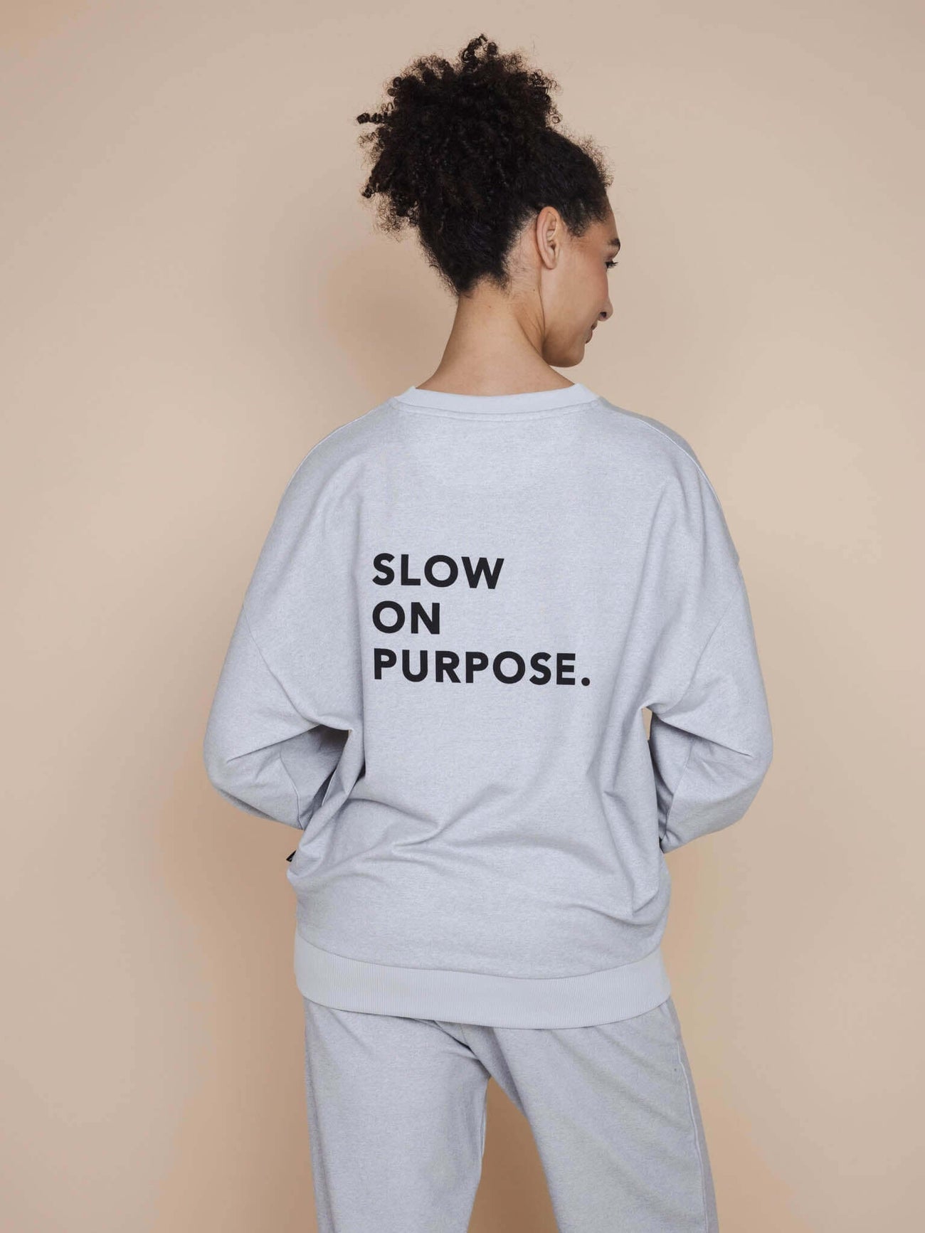 SNURK Slow Grey Sweater Unisex met tekst 'SLOW ON PURPOSE' op de rug.
