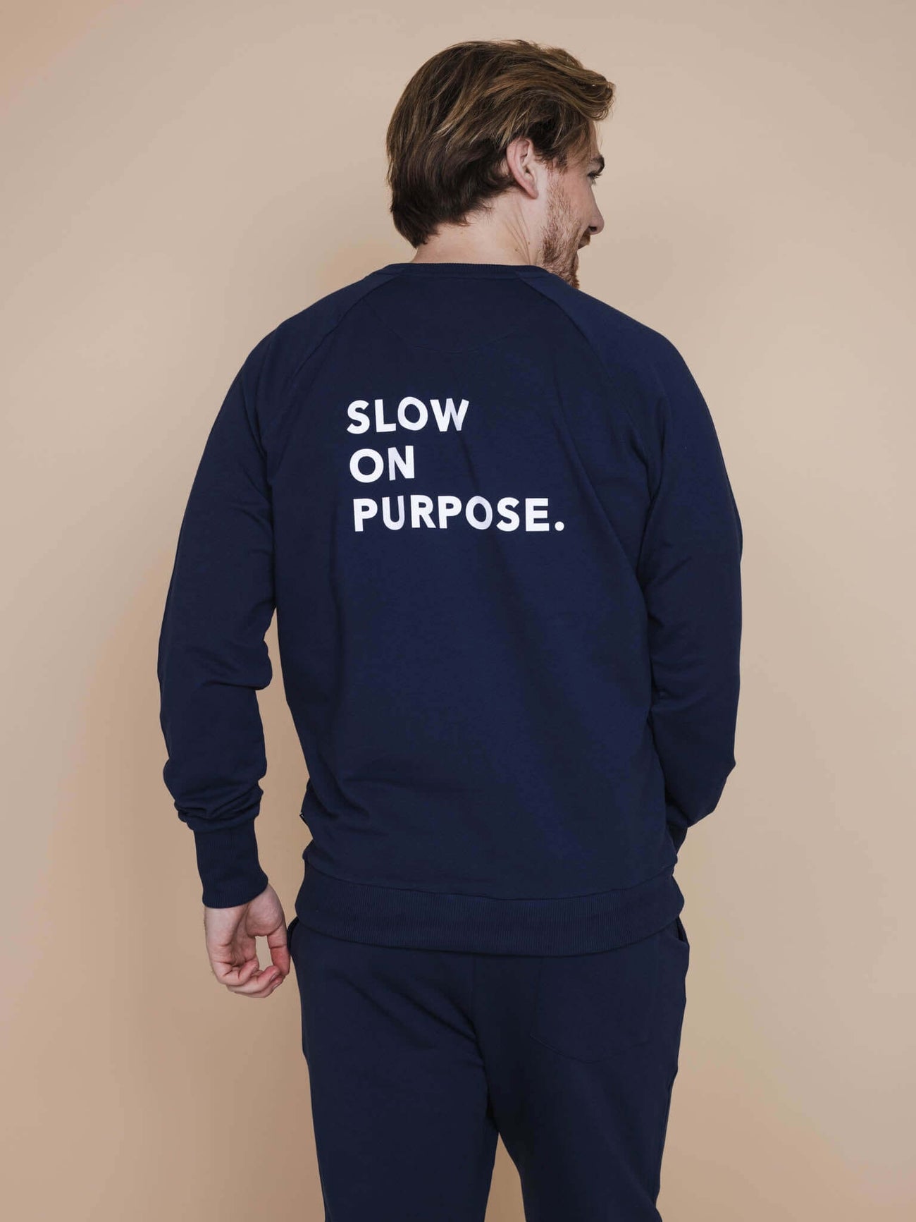 SNURK Slow Navy Sweater Heren met de tekst "SLOW ON PURPOSE" op de rug, ontspannen stylish heren outfit.