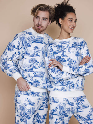 Modelen in SNURK Toile De Modern Joy Sweater Unisex met klassiek Frans motief en gamecontrollers op een neutrale achtergrond.